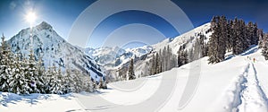 Three people hiking in mountains winter landscape with deep snow on clear sunny day. Allgau, Bavaria, Germany.