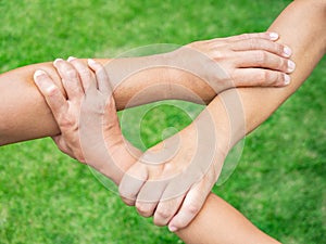 Three people join hands together on grass background. Friendship