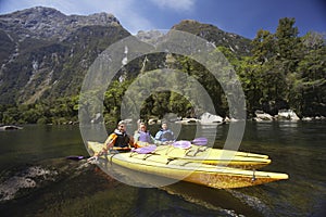 Three People Kayaking In Mountain Lake