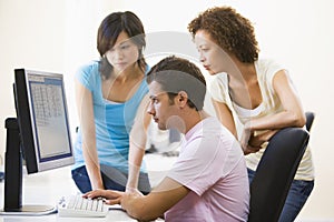 Three people sitting in computer room