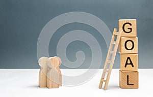 Three people are standing near the tower of cubes with the word goal. Business concept. cooperation and teamwork. Evaluation