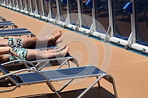 Three people sunbathing lying on deckchairs