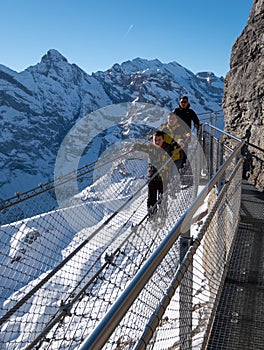 Three people walking on the Thrill Walk at Birg near Schiltorn in the Swiss Alps. It`s a steel pathway built into the mountainside