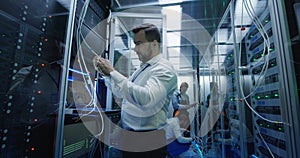 Three people working in a data center with cable