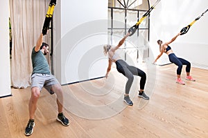 Three people working out doing Trx power pulls