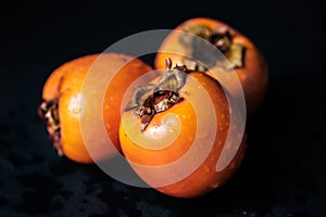 Three persimmon Kaki isolated on black background whole