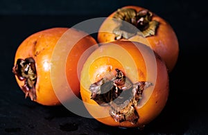 Three persimmon Kaki isolated on black background whole