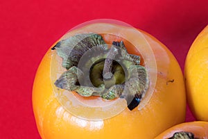 Three persimmons on red background