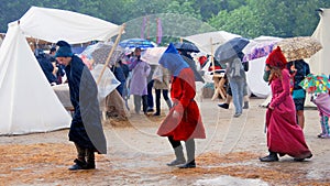 Three persons walk under the rain