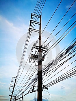 Three-phase electric poles on road side, that is common in Thailand. The electric lines, telephone lines and internet lines are w