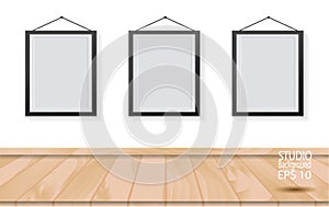 Three picture frames on wooden floor and white wall