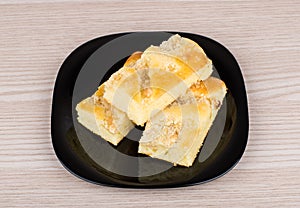 Three pieces of apple pie in black plate on table