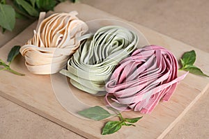 Three pieces of colorful raw italian fettuccine pasta with basil.