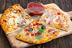 Three pieces of different pizzas on a wooden
