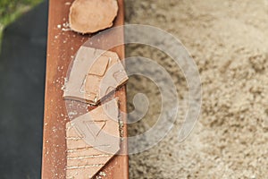 Three pieces of pottery in a sandbox