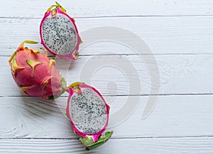 Three pieces of a red dragon fruit with black seeds on a white background