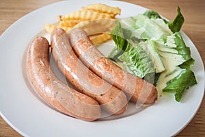 Three pieces of sausage with fresh vegetables, fried potatoes se