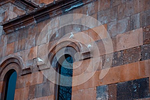 Three Pigeons are sitting on the armhole of the church