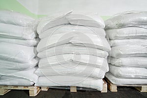 Three piles of big white sacks at large warehouse