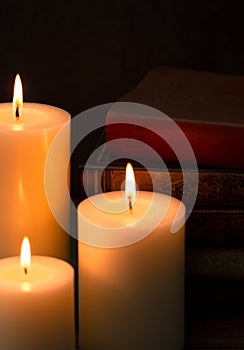 Three Pillar Candles Burning in a Dark Room with a Bible