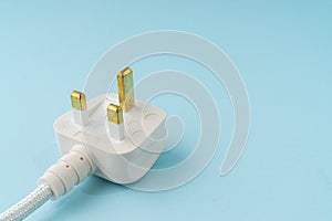 Three pin plug on light blue background with a copy space