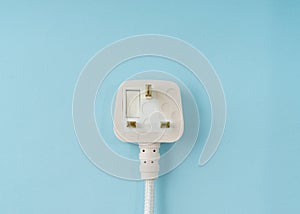 Three pin plug on light blue background with a copy space