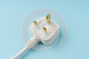 Three pin plug on light blue background with a copy space