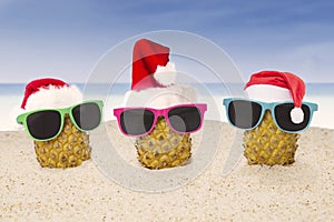 Three pineapple with Santa hat on beach