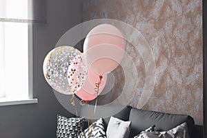 Three pink balloons for a girl's birthday in the interior of a dark room