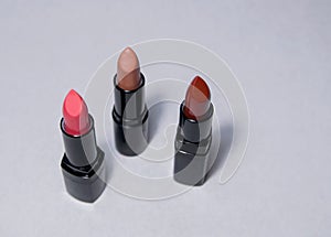 Three pink carrot and beige lipsticks stand upright photo