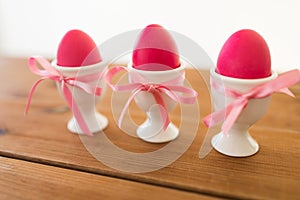 Three pink colored easter eggs in holders on table