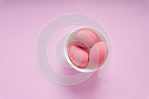 Three pink eggs inside the white bowl over pink background