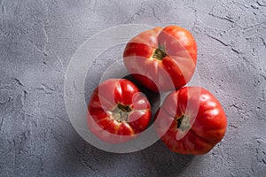 Three pink heirloom tomato vegetables, fresh red ripe tomatoes, vegan food, stone concrete background