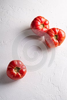 Three pink heirloom tomato vegetables, fresh red ripe tomatoes, vegan food, white stone concrete background