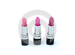 Three pink lipsticks in black case isolated on white
