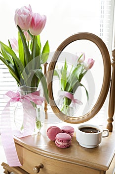Three pink macaroons and cup of coffee, pink tulips and mirror