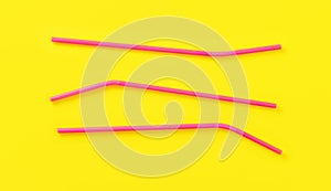 Three pink plastic drinking straws on yellow board, view from above