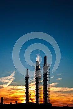 three pipes of a plant on a background of sunset and blue sky. S