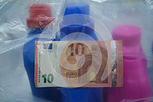 Three plastic bottles with a banknote inside an envelope. Plastic tax concept