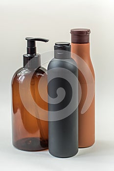 Three plastic bottles of cosmetics stand on a light background.