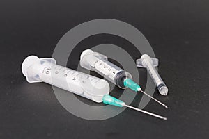 Three plastic disposable syringes on dark background