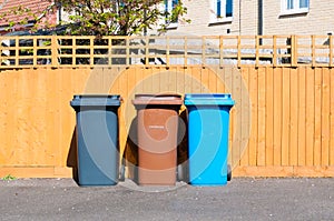 Three plastic waste bins outside a house
