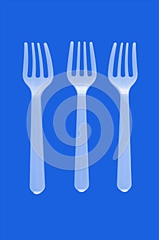 three plastic white forks on a blue background. isolate. Top view.