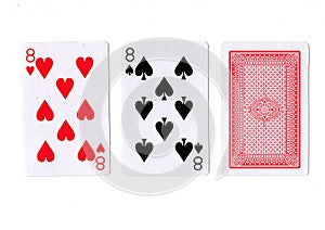 Three playing cards with a pair of eights revealed.