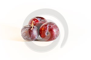 Three plums are blue on a white background