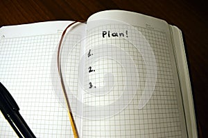 Three-point plan, schedule - Ð° notepad in a cage on a wooden background and the inscription with a black marker `plan 1, 2, 3`