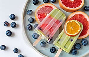 Three Popsicles on a Plate With Blueberries and Oranges