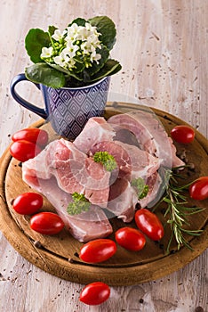 Three pork filets on chopping board with herbs and tomatoes