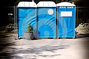 Three portable blue WC toilet cabins at construction site