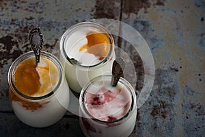 Three portions of fresh natural homemade organic yogurt in a glass jar on a vintage background